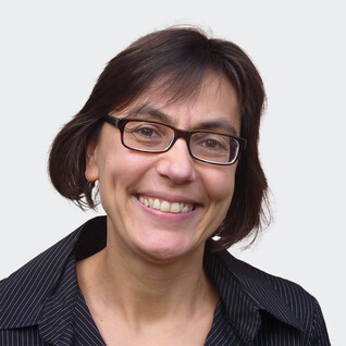 Frau mit dunklem, kurzem Haar und breitem Lächeln.